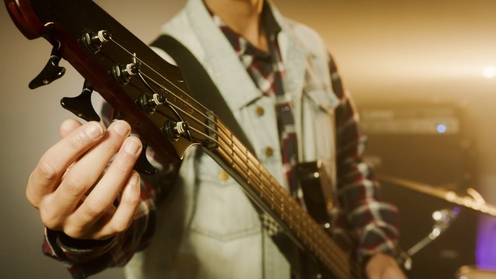 A Person Tuning a Bass Guitar