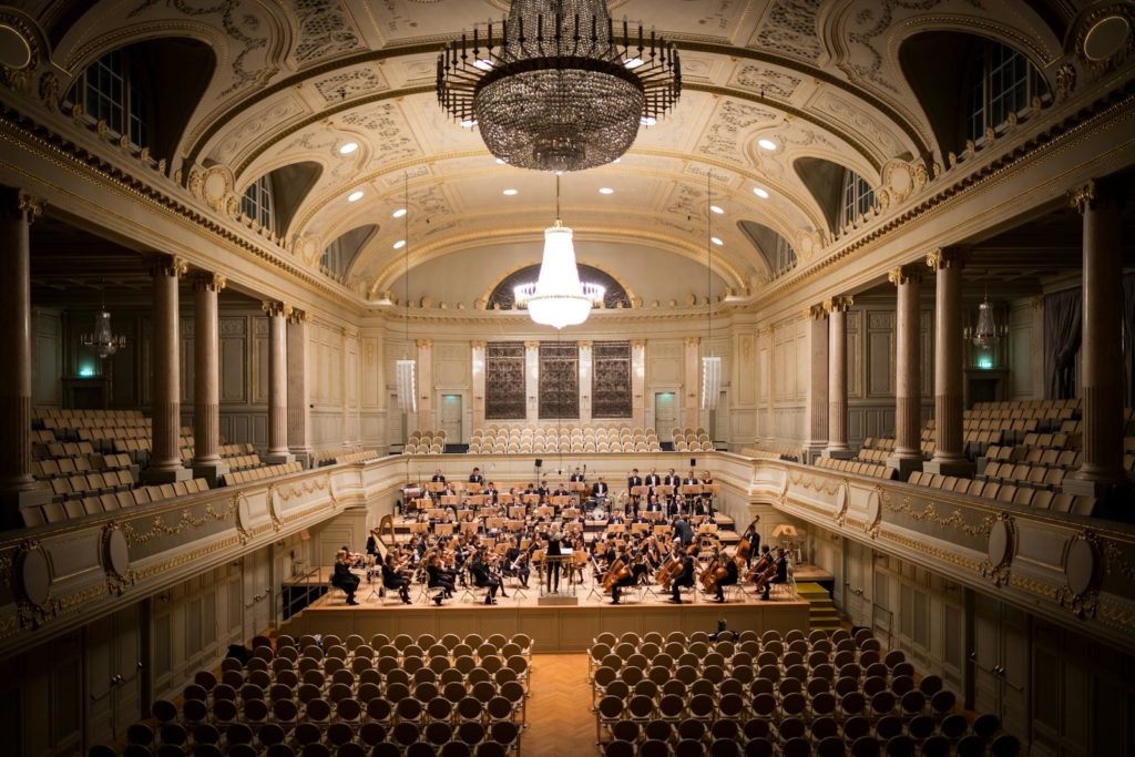 music group performing on stage with empty audience seats