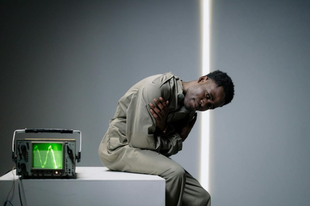 A Man Sitting on the Table Beside the Oscilloscope